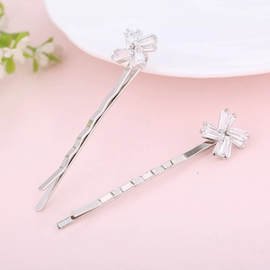 Dettaglio di fermagli per capelli a fiore in argento con zirconi su sfondo rosa tenue