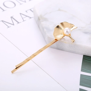Barrette à cheveux élégante en feuille de ginkgo dorée avec perle pour femme sur fond marbre