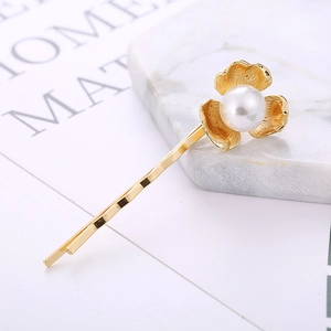 Barrette élégante en métal doré avec fleur de perle minimaliste sur une surface en marbre