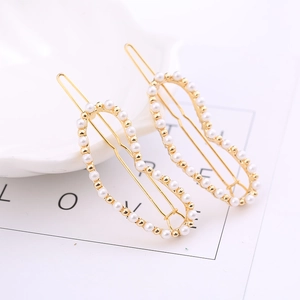 Detail von eleganten goldfarbenen Haarspangen mit kleinen weißen Perlen in Herzform