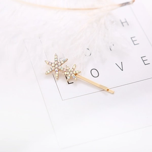 Detailed view of two gold snowflake hairpins with sparkling rhinestones and white feathers