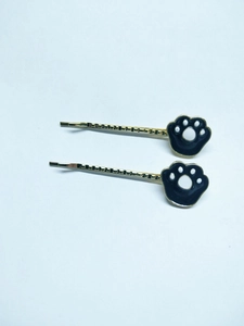 Detail of two cute black cat paw hair clips featuring gold metal and enamel finish