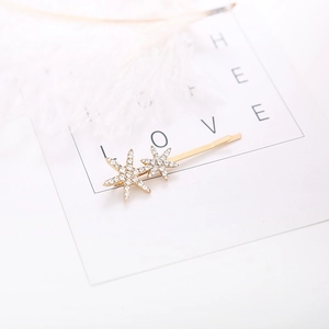 Sparkling gold star hair clip with rhinestones on a white feather and card display