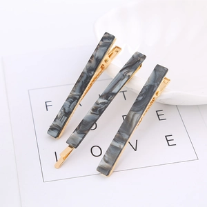 Close-up of three acetate marble texture hair clips with gold metal base on white card