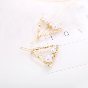 Detail of gold geometric hair clips with white pearls and rhinestones on white background
