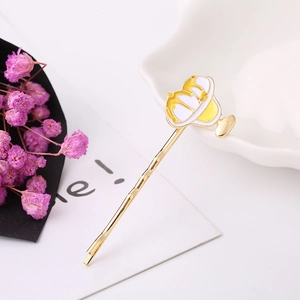 Nahaufnahme der goldenen Haarspange mit gelb-weißem Emaille-Dessert-Motiv-Design
