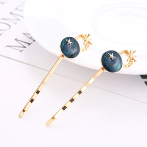 Détail de barrettes dorées lune et étoiles avec motifs de ciel étoilé bleu profond