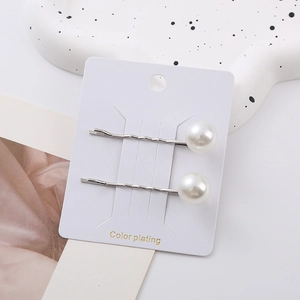 Detail of silver plated wavy hairpins with glossy white pearls on a display card