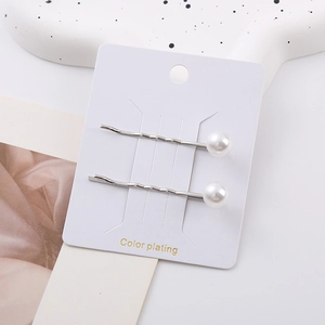 Detailed view of silver wave hair clips with white pearls on craft display card