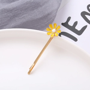 Detailed close-up of a daisy floral hair clip with yellow petals on a gold metal barrette