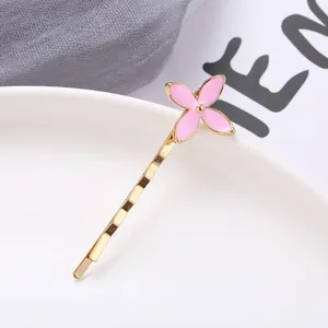 Detail of a golden sunflower hair clip with pink enamel petals on a ceramic plate