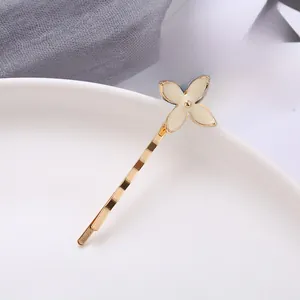 Close-up of golden sunflower four-leaf clover hair clip on white ceramic plate