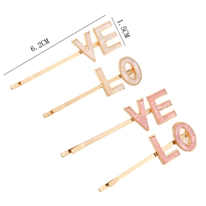 Detail view of pink and white LOVE acetate letter hair clips on gold metal pins