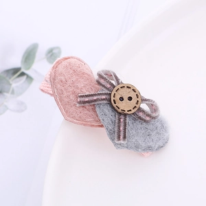 Barrette à cheveux cœur en feutre rose avec bouton en bois sur assiette blanche