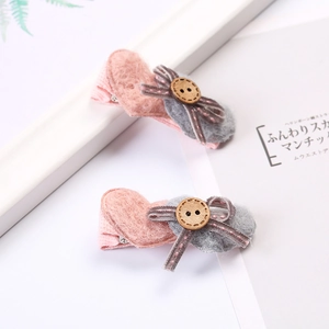 Détail de pinces à cheveux cœur en feutre rose et gris avec boutons et nœuds en ruban