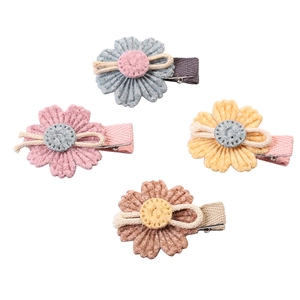 Set mit vier bunten Gänseblümchen-Haarspangen aus Stoff in Rosa, Blau, Gelb und Braun