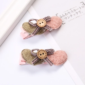 Détail de barrettes à cheveux avec nœud, base en peluche de cœur et bouton en bois