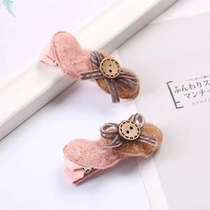 Détail de barrettes à nœud en feutre avec boutons en bois décoratifs en rose et marron