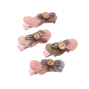 Détail de quatre barrettes à cheveux en feutre en forme de cœur avec nœuds et boutons