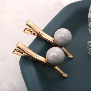 Paire élégante de barrettes dorées ondulées avec de grandes perles rondes et brillantes