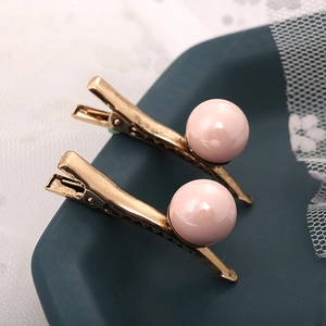 Vue détaillée de pinces à cheveux en bronze vintage avec des perles roses lustrées