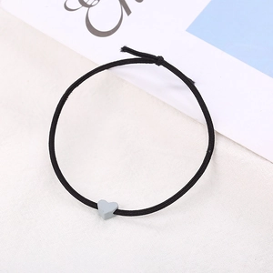 Dettaglio di elastico per capelli nero minimalista con perlina a forma di cuore grigio