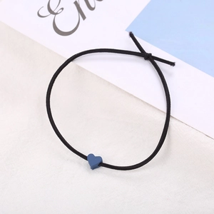 Dettaglio di un elastico per capelli nero con una piccola perla a cuore blu opaco su bianco
