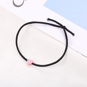Dettaglio di un elastico nero per capelli con un ciondolo a forma di cuore rosa opaco moderno