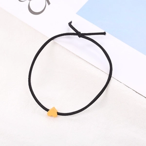 Dettaglio di un elastico per capelli nero con una perla a cuore gialla opaca su tela