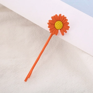 Detail van de oranje madeliefje haarspeld op een witte linnen stoffen achtergrond