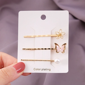 Drei Haarspangen im Set mit goldener Blume, rosa Schmetterling und weißen Perlen im Detail