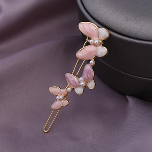 Detailansicht der goldfarbenen Schmetterlingsspange mit rosa Emaille und Kunstperlen