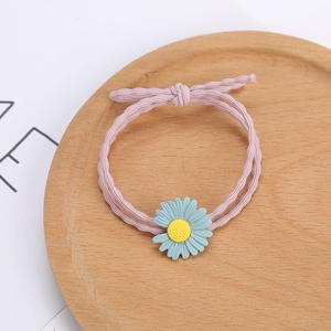 Élastique à cheveux rose avec fleur de marguerite bleue sur un plateau en bois