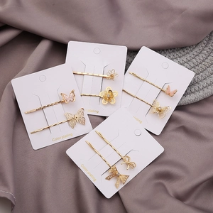 Set of minimalist golden flower and hollow butterfly hair clips on silk fabric