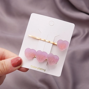 Détail des barrettes cœur dégradé rose et violet avec texture sucre et placage doré