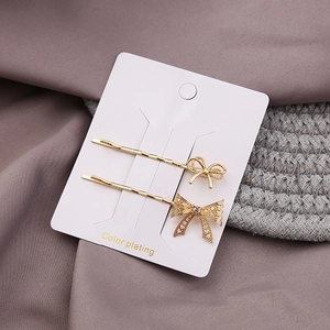 Detail view of two gold bow hair clips with solid and hollow rhinestone designs