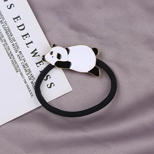 Detail of panda hair tie with gold-edged metal charm on high elastic black band