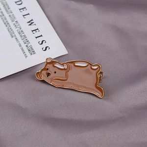 Close-up of cute brown cartoon bear hair clip with enamel finish on textured background