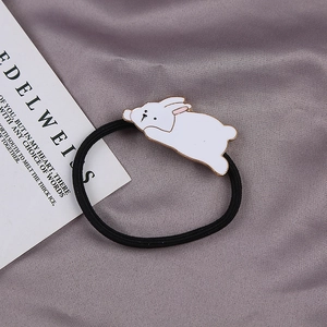 Detail of high-elasticity black hair tie with cute white rabbit charm on silk fabric