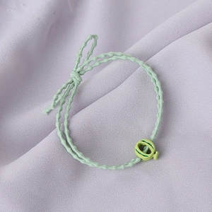 Gros plan d'un chouchou tressé vert menthe avec pendentif ajouré sur un tissu de fond violet