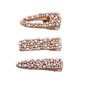 Three-piece set of elegant gold alloy hair clips with white faux pearls on white background
