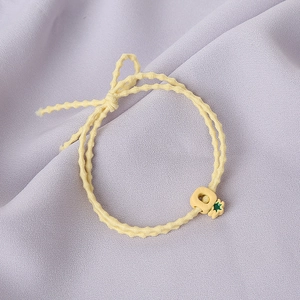 Détail de l'élastique à cheveux jaune avec breloque fruit sur fond de tissu violet