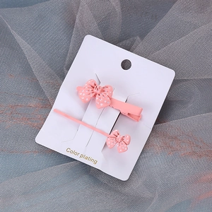 Ensemble de barrettes à nœud rose à pois avec pince crocodile sur carte blanche