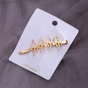 Close-up of golden tribal fire-shaped hair clip with polished plating on display card