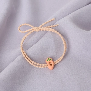 Gros plan d'un élastique à cheveux orange avec un pendentif carotte et un joli nœud