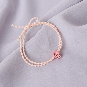 Détail de l'élastique à cheveux rose avec pendentif carotte sur tissu violet doux