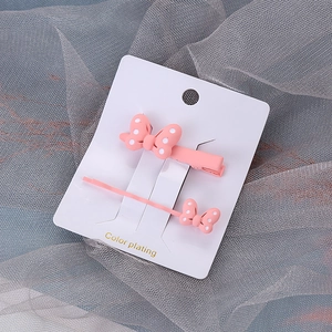 Gros plan de pinces à cheveux roses à pois avec nœud sur support en carton blanc