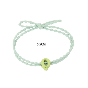 Détail d'un élastique à cheveux vert clair avec un nœud papillon et une perle en forme de Q