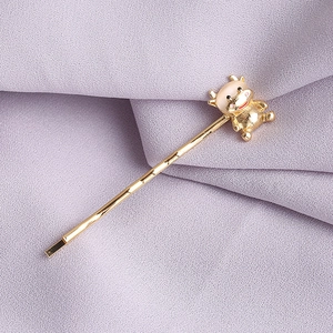 Barrette dorée en forme de bœuf avec émail rose sur un fond en tissu violet élégant