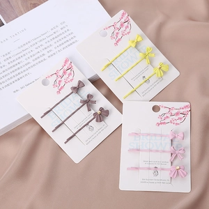 Détail de trois ensembles de barrettes à nœuds en jaune, marron et rose sur magazine